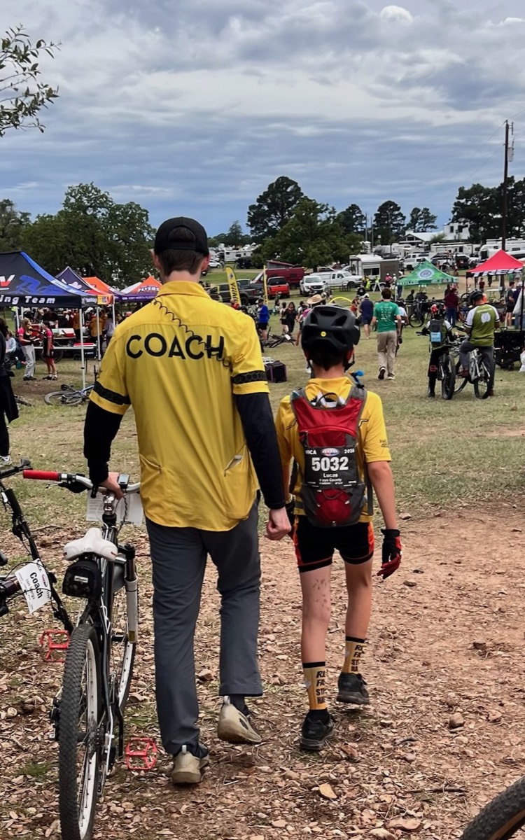 A Stingers coach walking alongside a young rider at a race