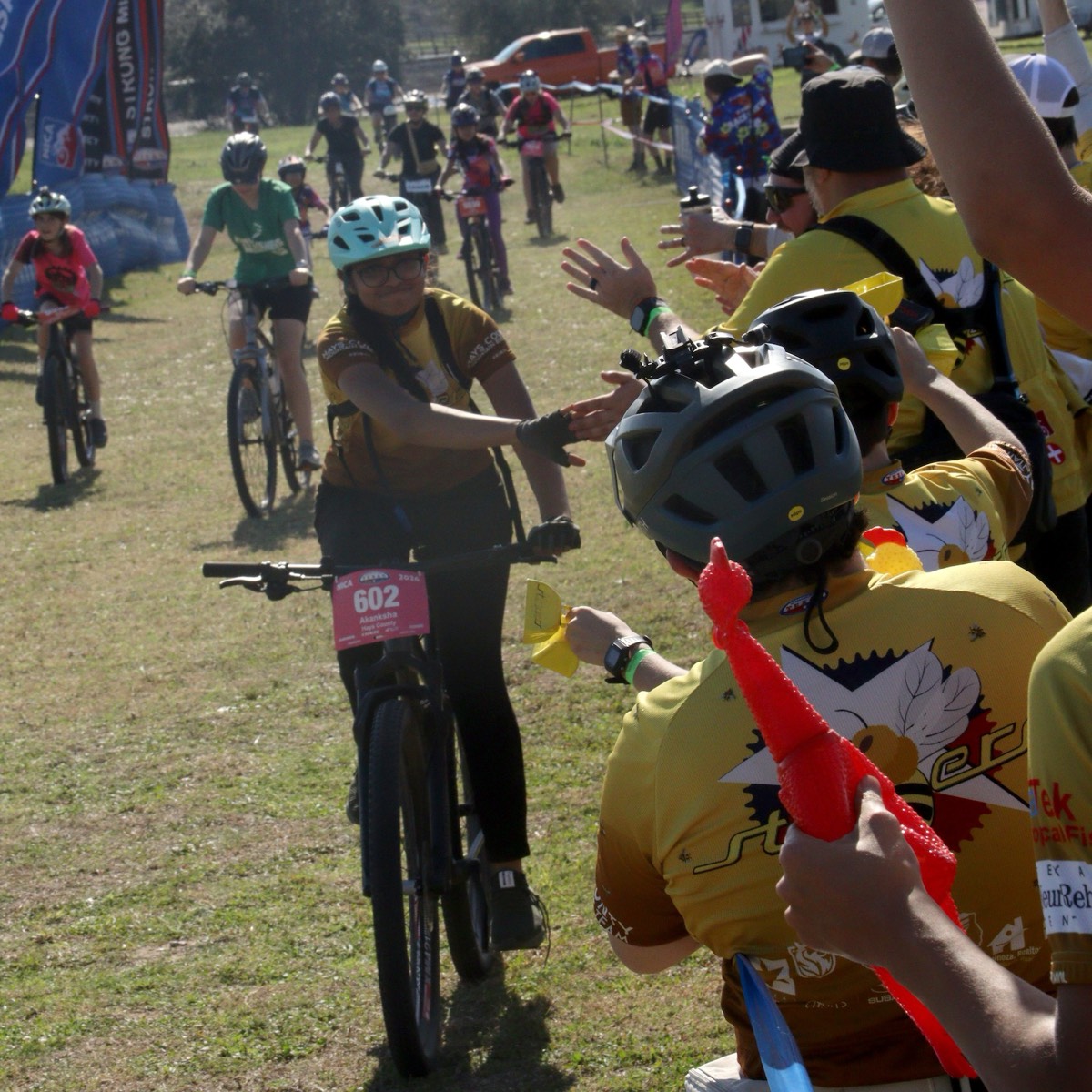 Teammates cheering a Stingers rider across the finish line