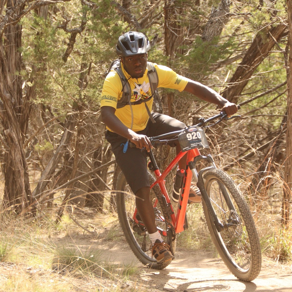 A Stingers rider racing through wooded singletrack